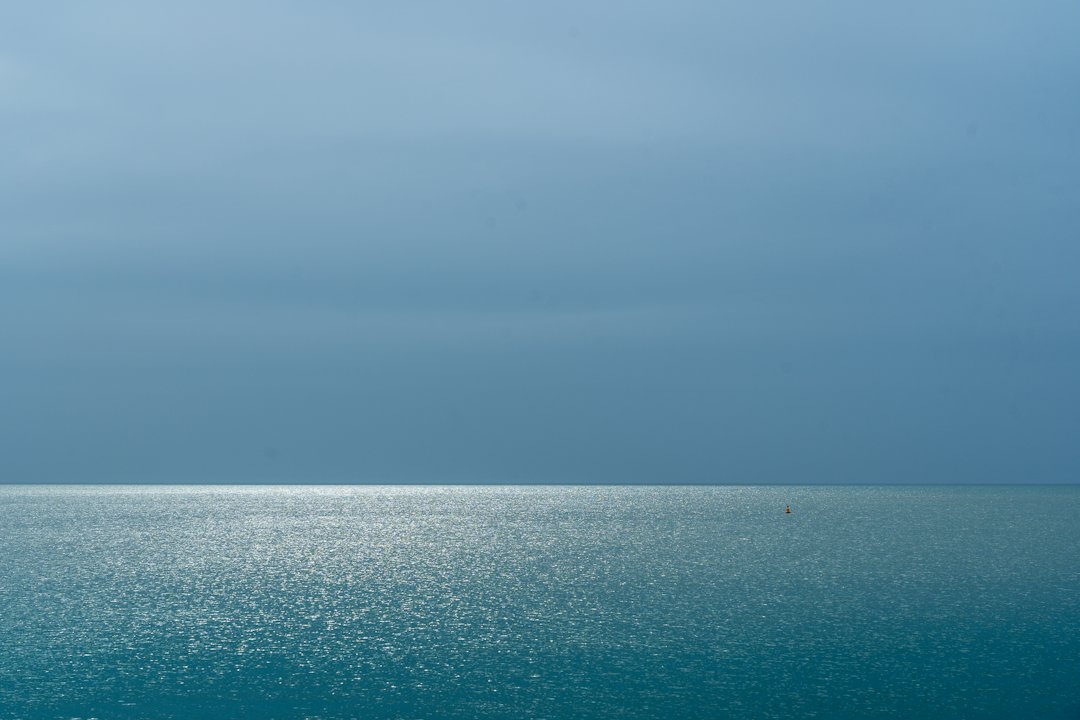 Mer étale sous un ciel couvert, jusqu'à l'horizon